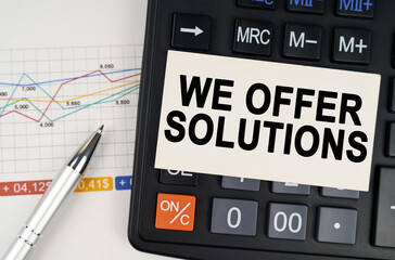 On the business chart lies a pen, a calculator and a business card with the inscription - We Offer Solutions