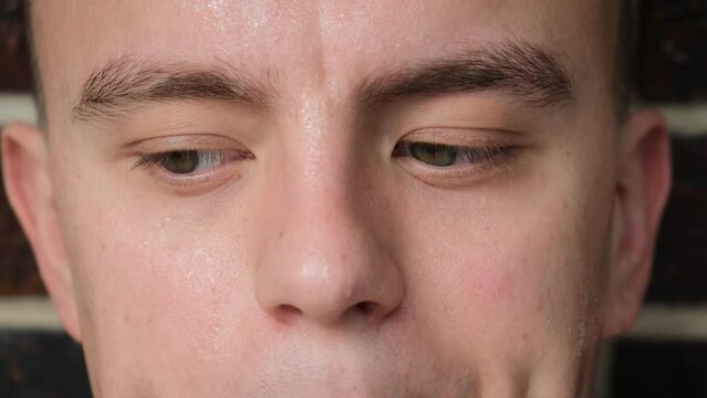 Sweaty face of a worried man with shifty eyes, close-up