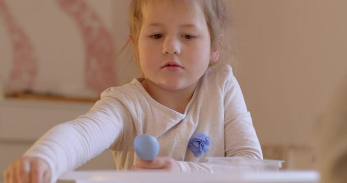 Child with an autism. Girl portrait during free psychotherapeutic behavioral correction session. Caring for mental health. Baby takes small objects, speaks.