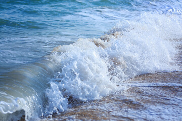 Ocean waves crashing on sandy beach. Sea waves breaking on shore. Nature splash on summer day. Sea wave crashing on beach. Splashing sea water with foam.