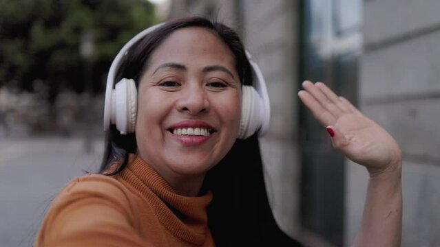 Happy Asian woman streaming on social media with city on background