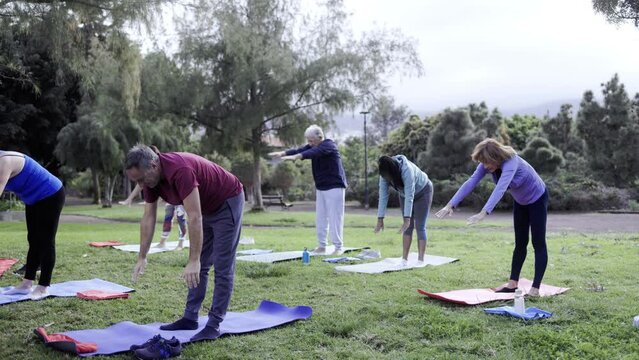Senior people exercising in yoga class outdoor at park city - Sport, older community concept