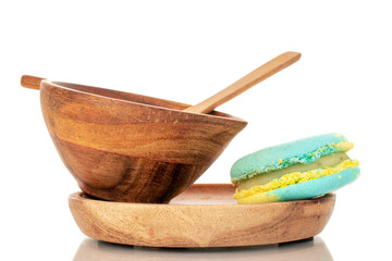 One confectionery product, sweet macaroon on wooden saucer with cup, macro, isolated on white background.