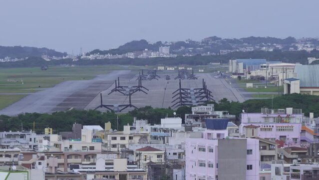 米軍普天間飛行場に駐機するオスプレイと飛び立つ軍用ヘリコプター