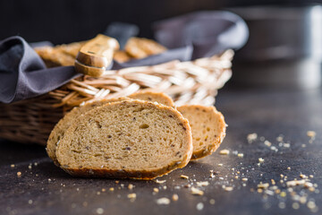 Naklejka premium Sliced whole grain bread. Tasty wholegrain pastry with seeds on black table.