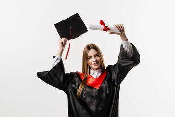 Graduate girl is graduating high school and celebrating academic achievement. Masters degree diploma in hands. Happy student in black graduation gown and cap is smiling on white background.