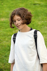 portrait of teenage girl with glasses with curly hair and a white T-shirt on outdoors