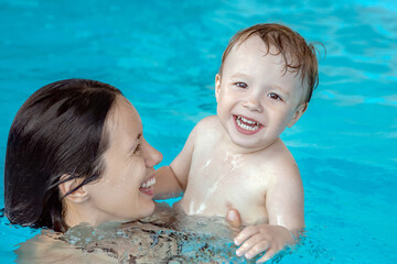 joyful baby with his mother swim in the pool, parents teach child to swim in children's pool