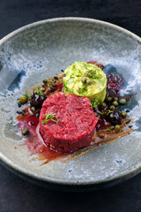 Modern style gourmet tartar raw from chianina beef filet with avocado and capers in amareno cherry...