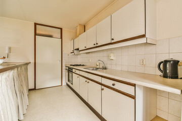 a kitchen with white cabinets and wood trim on the counter tops, along with an open door leading to...