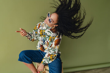 attractive black african american woman in stylish outfit on green studio background
