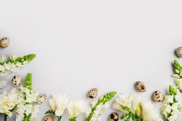 Happy Easter holiday mockup. Natural white freesia flowers, green branches and quail eggs on light...