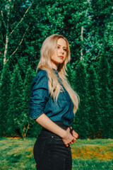 Beautiful blonde in demin shirt with trees on background in outdoor