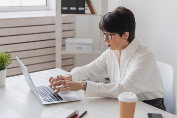 Attractive mature business woman working on laptop in her workstation - manager and office concept