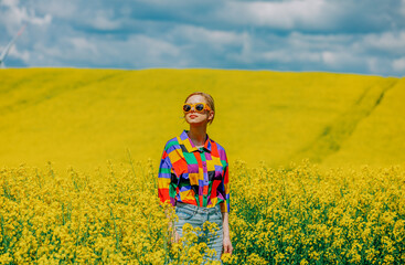Beautiful female in 90s stylish shirt in rapeseed field
