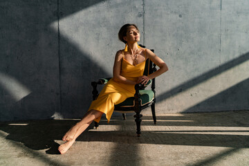 attractive woman in yellow summer dress in interior room concrete wall background