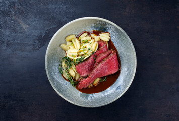 Traditionelles italienisches Chianina Roastbeef mit Gnocchetti-Sardi Nudeln in würziger Rotweinsoße serviert als Draufsicht in einer Nordic Design Schale mit Textfreiraum 