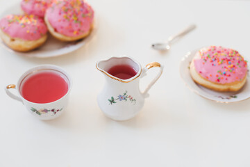 morning breakfast with colorful pink drink and donuts on white table. holiday, birthday party composition, flatlay top view