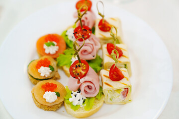 small sandwiches, rolls and burgers in a plate on the table.