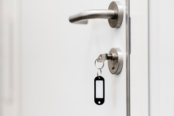 White door, door handle, door lock with key. Copyspace, place for text.