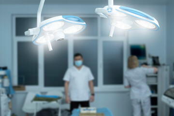 Closeup , operating lamp on in operating room, medical staff, doctor and nurse on blurred...