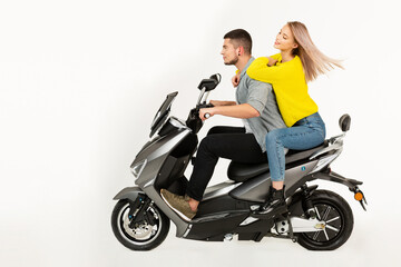 Plakat young attractive couple riding an electric motorbike scooter happy having fun together