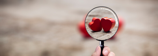 2 beautiful red hearts on a table focused by a magnifying glass
