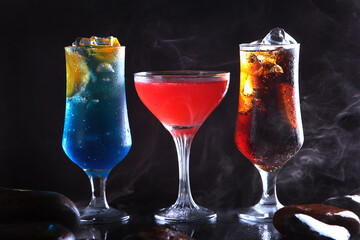 An assortment of cocktails on a dark background. The classic concept of the drinks menu.Three refreshing cocktails on a black background. The bar counter in the restaurant. The range of drinks.