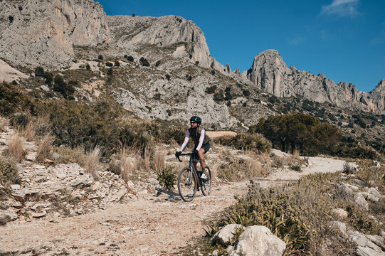 Men riding gravel bike on gravel road in mountains with scenic view  in Alicante region.Man cyclist  wearing cycling kit and helmet.Beautiful motivation image of an athlete.Serra de Bèrnia,Spain.