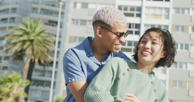 Happy biracial couple embracing on promenade, in slow motion