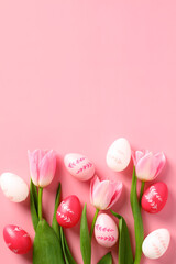 Happy Easter holiday concept. Vertical banner design with tulips and Easter eggs on pink background. Flat lay, top view.