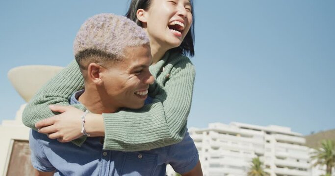 Happy biracial couple embracing on promenade, in slow motion