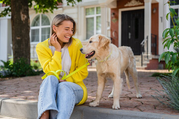 happy smiling woman in yellow sweater walking at her house with a dog golden retriever