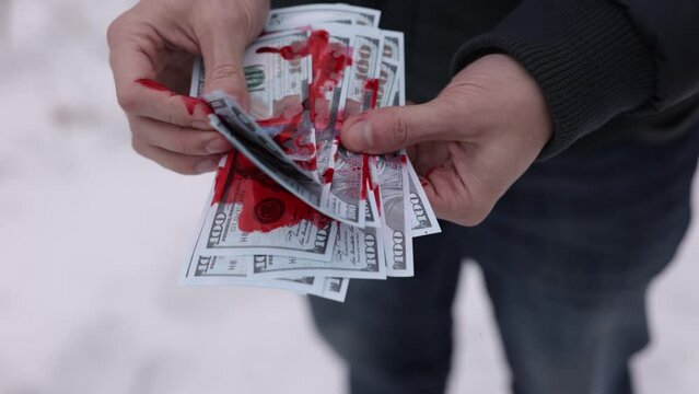Blood on cash, Illegal earnings, Dirty money. A pile of money stained with blood is being counted by a man's hands.