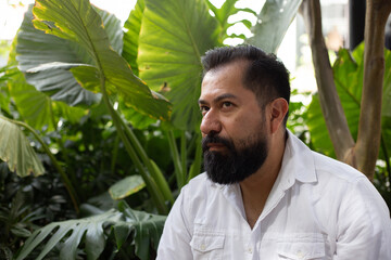 Naklejka na ściany i meble Retrato de hombre mexicano en edad adulta , con barba, plantas en su entorno, camisa blanca y pantalón beige