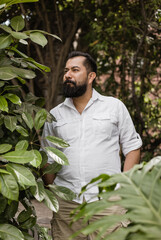 Retrato de hombre mexicano en edad adulta , con barba, plantas en su entorno, camisa blanca y...