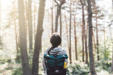 Unrecognizable teenager in the mountains, looking at the landscape with an adventure backpack