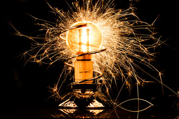 Isolated sparkling exploding electric light bulb on black background