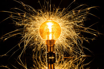 Isolated sparkling exploding electric light bulb on black background