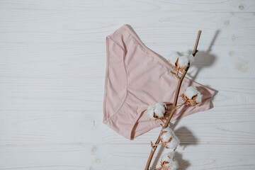 Pink underpants with cotton brunch on wooden background, closeup