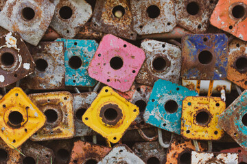 Old scaffold tubes are stored outside in a pile. Different colors yellow pink green tubes baseplates. Parts of the scaffolding. Scaffolding base vintage wallpaper. Standard workpiece scaffolds.