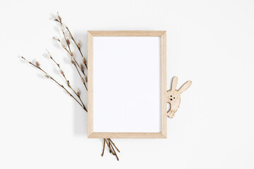 Easter trendy composition. Photo frame top view, willow plant branches, easter eggs and bunny on...