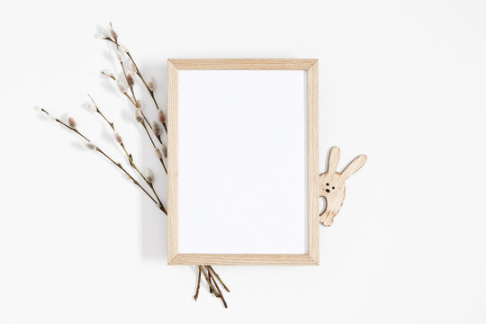 Easter trendy composition. Photo frame top view, willow plant branches, easter eggs and bunny on white background. Minimal concept Easter. Flat lay, top view, copy space