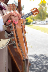 mariachi woman group, female mariachi hands holding a big guitar, fingers detail of a hispanic feminine musician