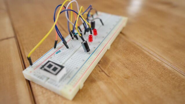 Breadboard with electrical elements, on a wooden table.