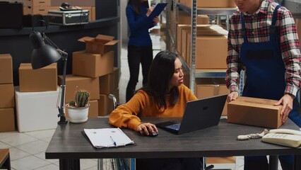 Young employee with impairment working in warehouse, doing desk work for stock logistics and inventory on laptop. Woman wheelchair user doing financial planning in disability friendly space. - Powered by Adobe
