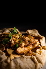 Rustic apple galette on parchment paper garnished with a sprig of mint.