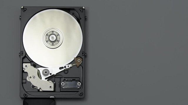 The disassembled hard drive works, spins, reads information. Spare parts from the computer. Memory devices. On a black background.