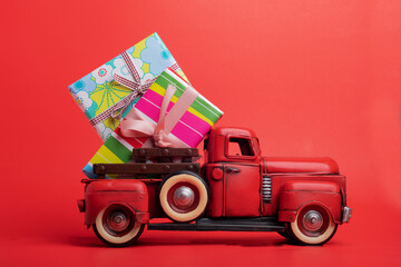 Red vintage truck with bright gifts on a red background