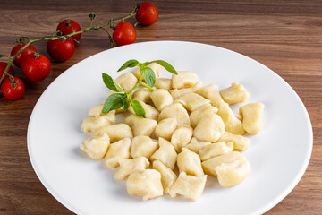 BAKED GNOCC IN A WHITE PLATE ON A WOODEN BACKGROUND.